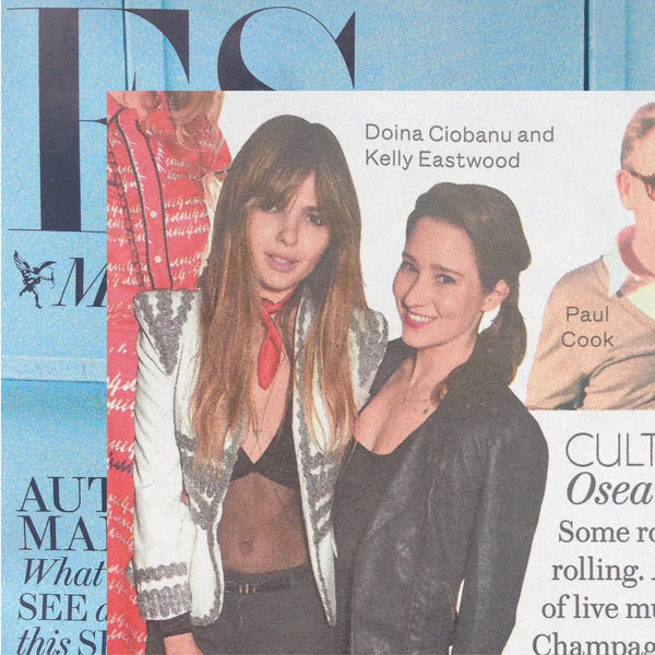 A cropped magazine cover featuring two women standing together, with visible text including 'Doina Ciobanu and Kelly Eastwood'. The cover also includes partial masthead of ES magazine text and a blue-toned background. Doina is wearing the Fan body chain