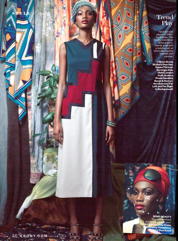A fashion editorial page featuring a model wearing a sleeveless midi dress with a bold geometric color-block pattern in navy, red, white, and black. The background is filled with colorful patterned textiles, and there is a small inset photo in the bottom right corner.