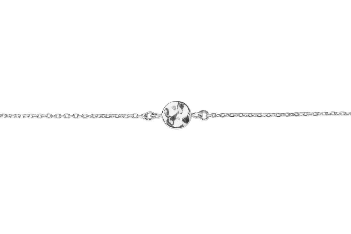 A delicate silver chain bracelet featuring a central round polished melted effect disk, set against a plain white background.