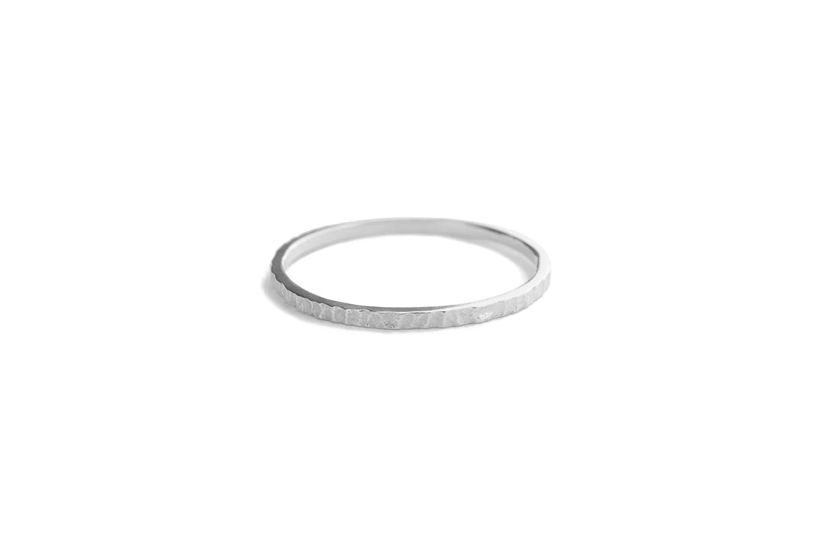 A thin silver band ring with a textured, hammered surface, shown against a plain white background.