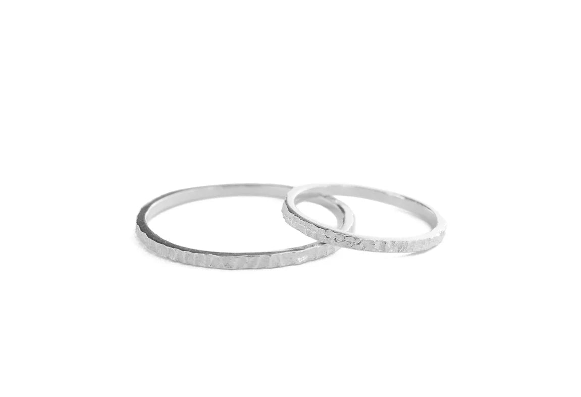 Two thin textured silver rings overlapping on a plain white background.