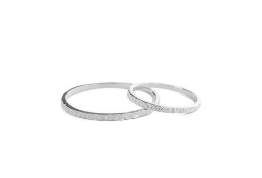 Two thin textured silver rings overlapping on a plain white background.