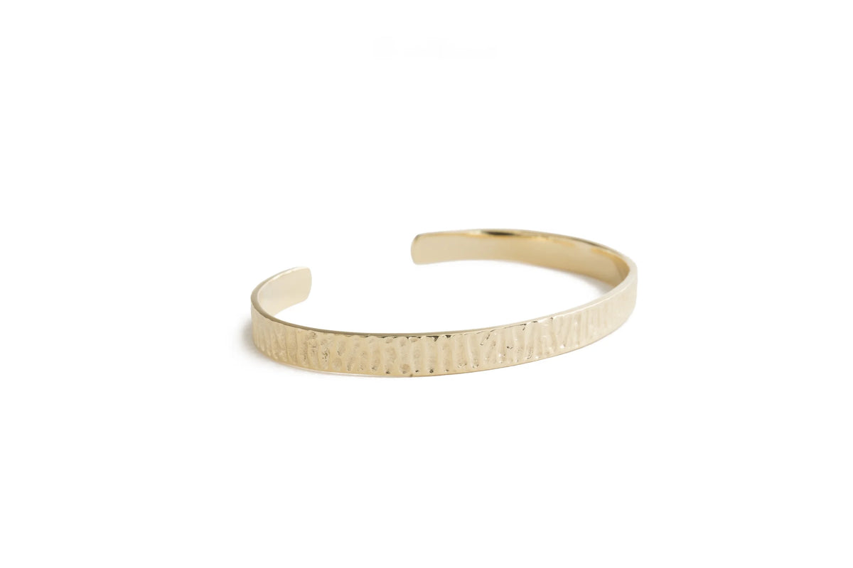 A textured gold cuff bracelet with a hammered finish, displayed on a clean white background.