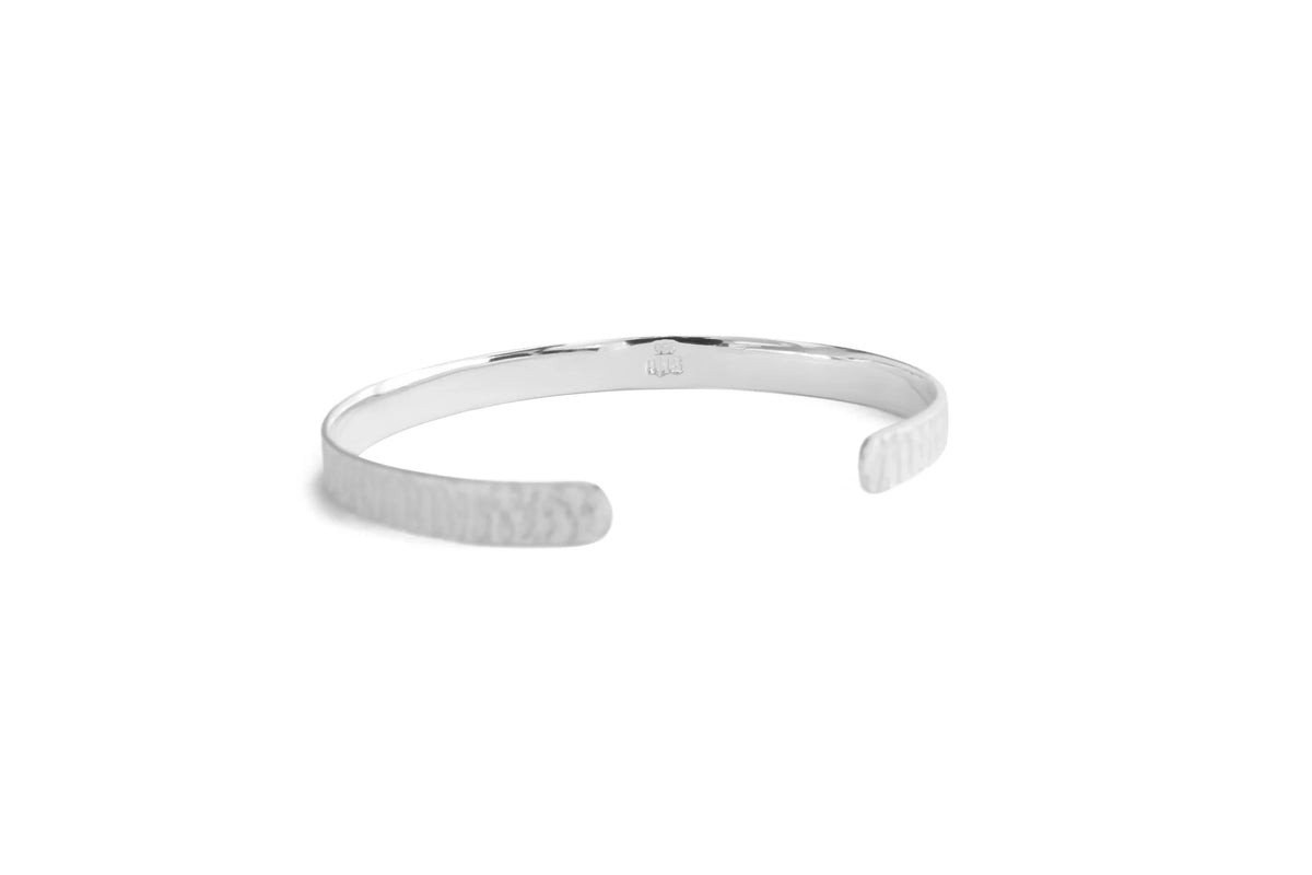 A silver open cuff bangle bracelet with a textured hammered finish on one side and a smooth polished finish on the inside, shown on a plain white background.