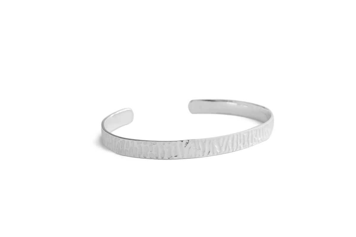 A textured silver cuff bracelet with a hammered finish, displayed on a clean white background.