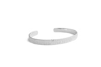 A textured silver cuff bracelet with a hammered finish, displayed on a clean white background.