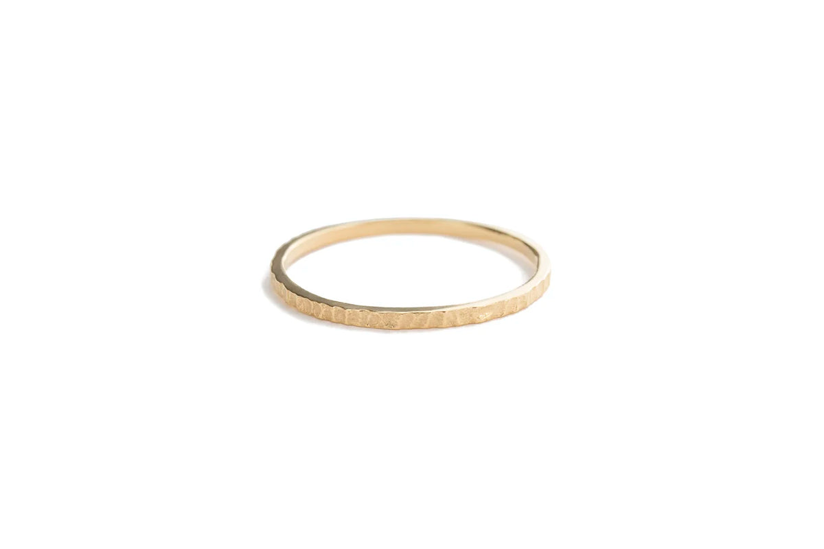 Gold ring with textured band on a white background