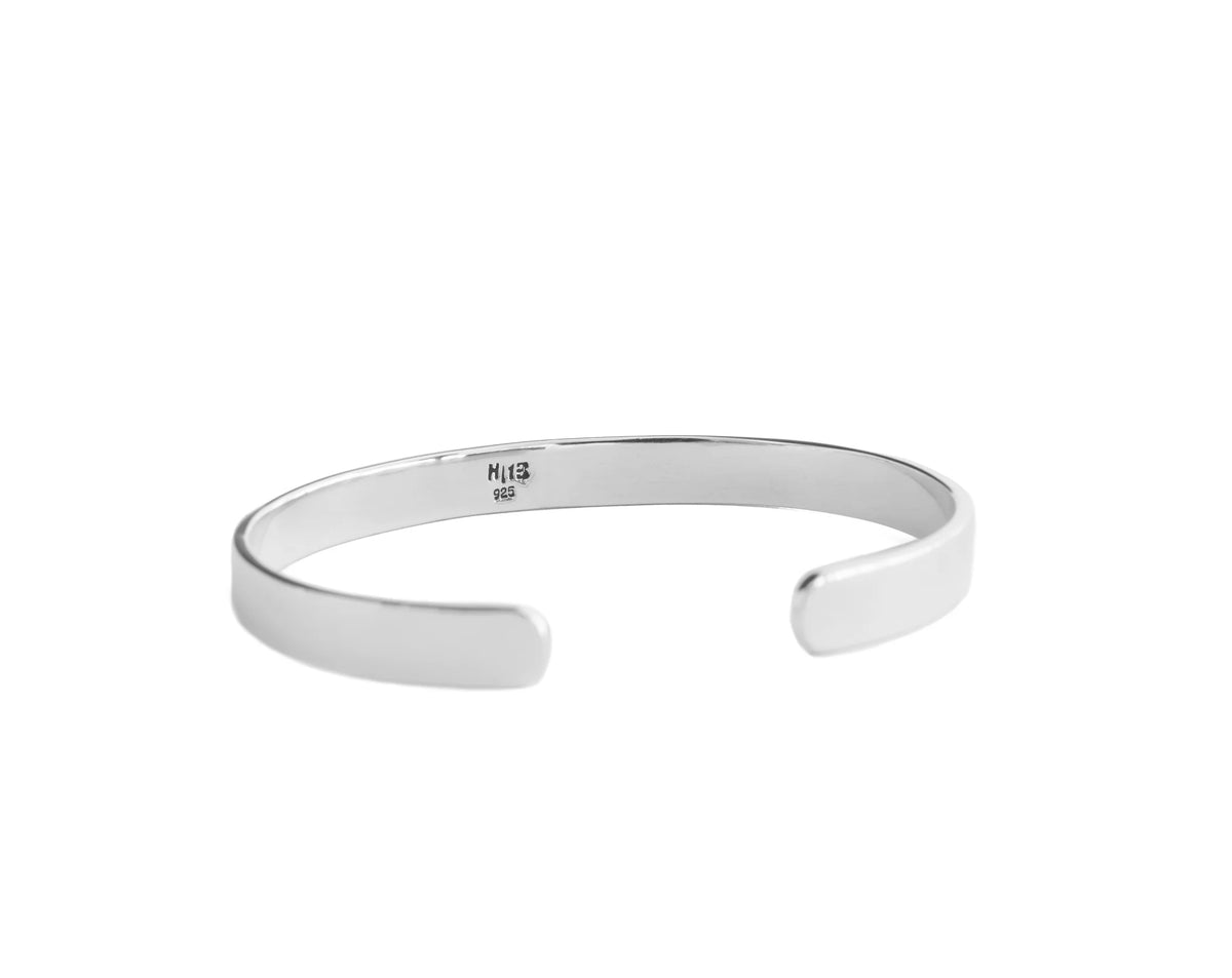 A minimalist silver open cuff bangle bracelet with a polished finish, featuring a small '925' sterling silver hallmark on the inner band, set against a plain white background.