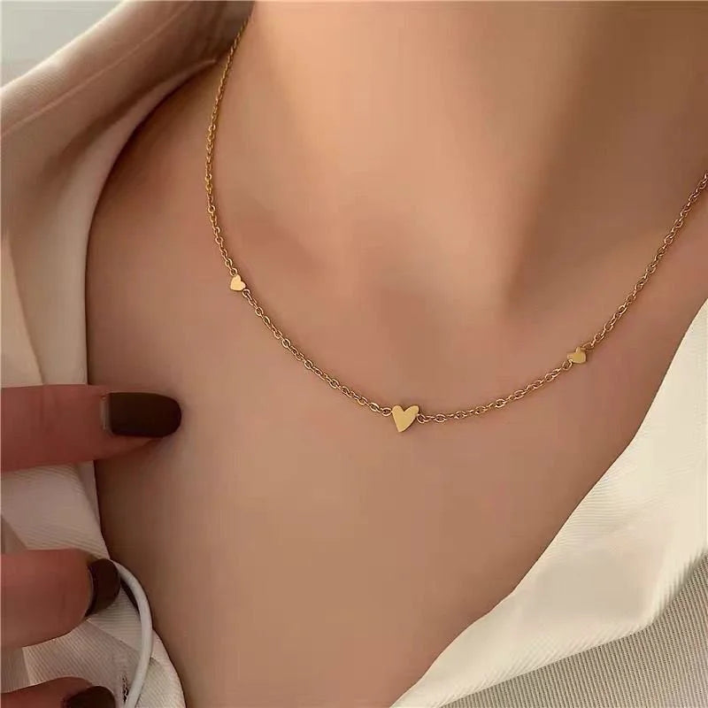 Gold heart necklace featuring 3 small hearts on a person's neck 