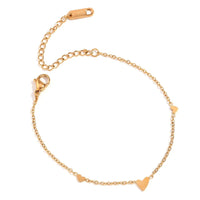A delicate gold chain bracelet with three small heart charms, displayed on a clean white background.