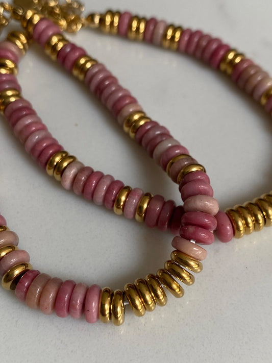 A close-up of a beaded bracelet made of and gold beads, photographed on a plain light background.