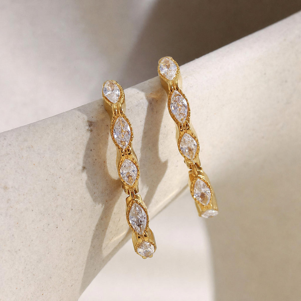 Gold hoop earrings with clear cubic zirconia crystals, on a light background