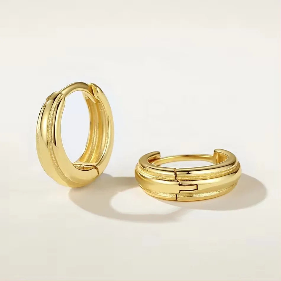 A pair of gold-plated Stack huggie hoop earrings with a textured, ribbed outer band displayed on a clean off-white background.