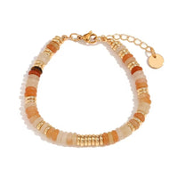 A beaded bracelet with alternating orange, peach, and soft yellow gemstones, accented by gold spacer beads and a gold clasp with an extender chain and round tag, shown on a white background.