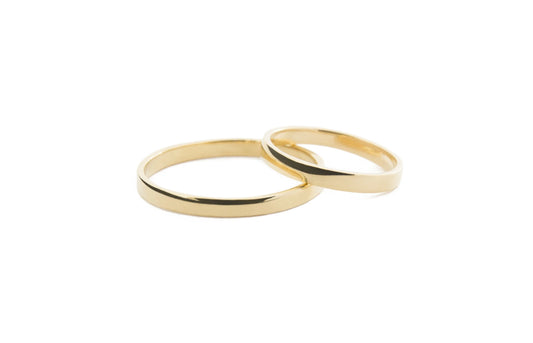 Two slim gold ring bands interlocking on a plain white background.