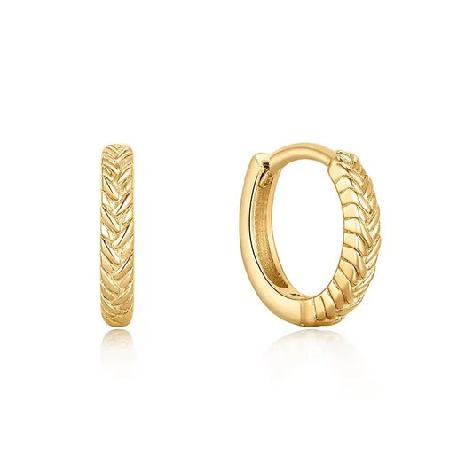 A pair of gold Braid huggie hoop earrings with a textured chevron pattern, shown from both front and side angles on a white background with soft reflections.