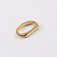 A gold slim signet-style ring with a polished, rounded rectangular face, shown on a clean white background.
